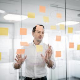 Riley T. planning cloud architecture with sticky notes and diagrams on a glass wall